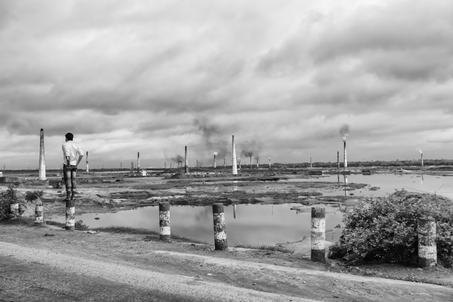 Man staying in front of brick factories chimneys, , Brick kiln factories site near Dhaka, Bangladesh, Indian Sub-Continent, Asia