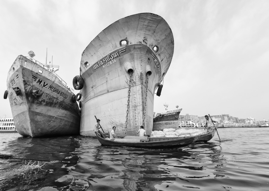 Typical small bangladeshi canoes sailing near huge river ships, The Buriganga River, Dhaka, Bangladesh, Indian Sub-Continent, Asia