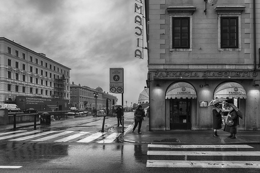 Two ladies chatting on a street in Trieste on a rainy day, Italy