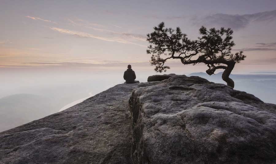 man sitting in beautiful foggy landscape