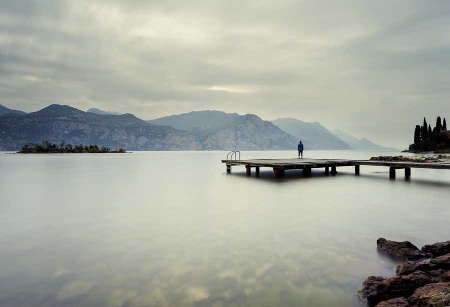 Man stand on a pier and watching the mountains and lake