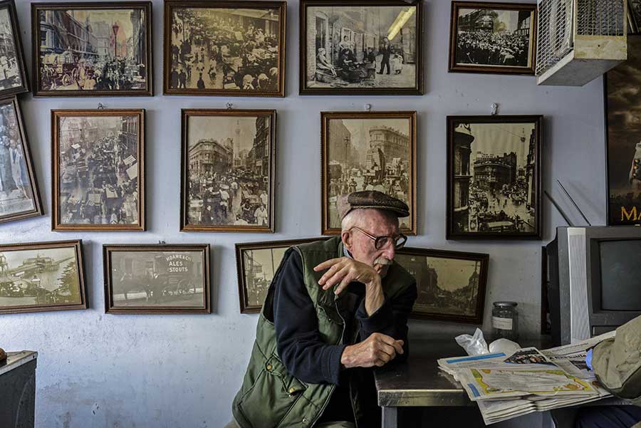 Disappearing Home-London East End's English community. 15. Mr Broomfield, fishmonger and former photographer, surrounded by his photographs of the London old Billingsgate Fish Market at the George's Plaice, Roman Road, Bow on the 11th March 2015, London.