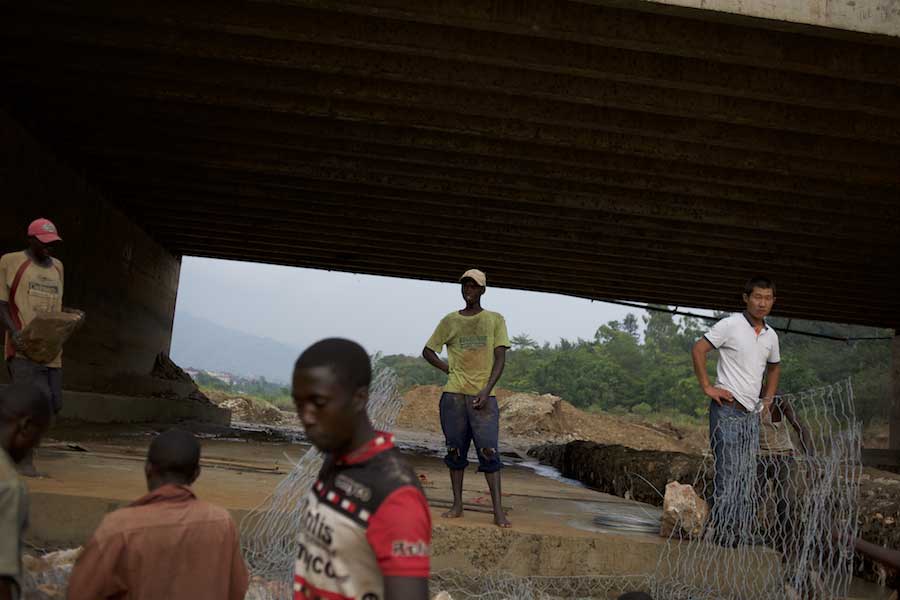 Local men are monitored by a Chinese engineer during the construction of a dam to prevent the erosion of the support pillars of a bridge in central Bujumbura, Burundi.