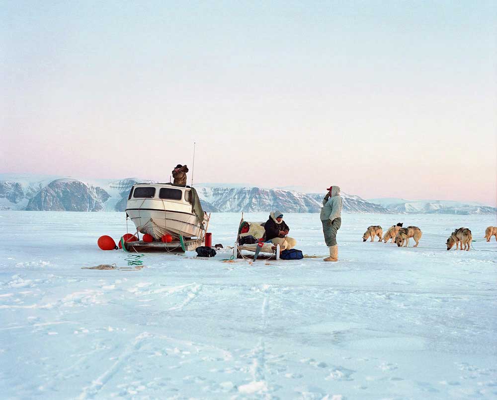 The hunting of sea mammals also occurs in the north of the country, and involves a journey across forty kilometers of sea ice to reach the open water. Even if the hunters in Qaanaaq are the last to still master the ancestral kayak hunting technics, more modern boats are also used to get closer to the mammals. The boat is pulled on a sled from town. The sleds are often grouped into “ropings” to optimize the dogs’ combined force, but many breaks are still required to give the animals the rest they need. After a seven-hour journey from Qaanaaq we meet another group of hunters already there. “Siku a jor- poq” says one of them : “the ice is bad”, we have to move and look for another place. Cell phones are used frequently, as is the case here, to keep abreast of the shifting weather – a telltale sign of the changing times. (Remark: here the hunter is having a call to Ikuo Oshima, a famous Japanese hunter who settled in Siorapalukin 1972)