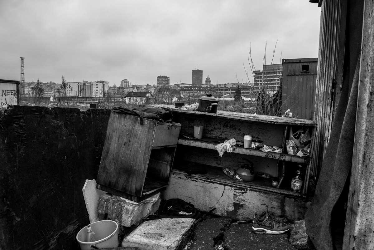 In the foreground, a makeshift outside kitchen in temporary shelter, and in the background Belgrade developing city.
