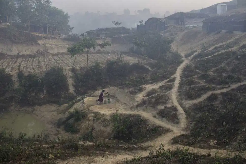 A Rohingya refugee girl collects water from a hand pump.